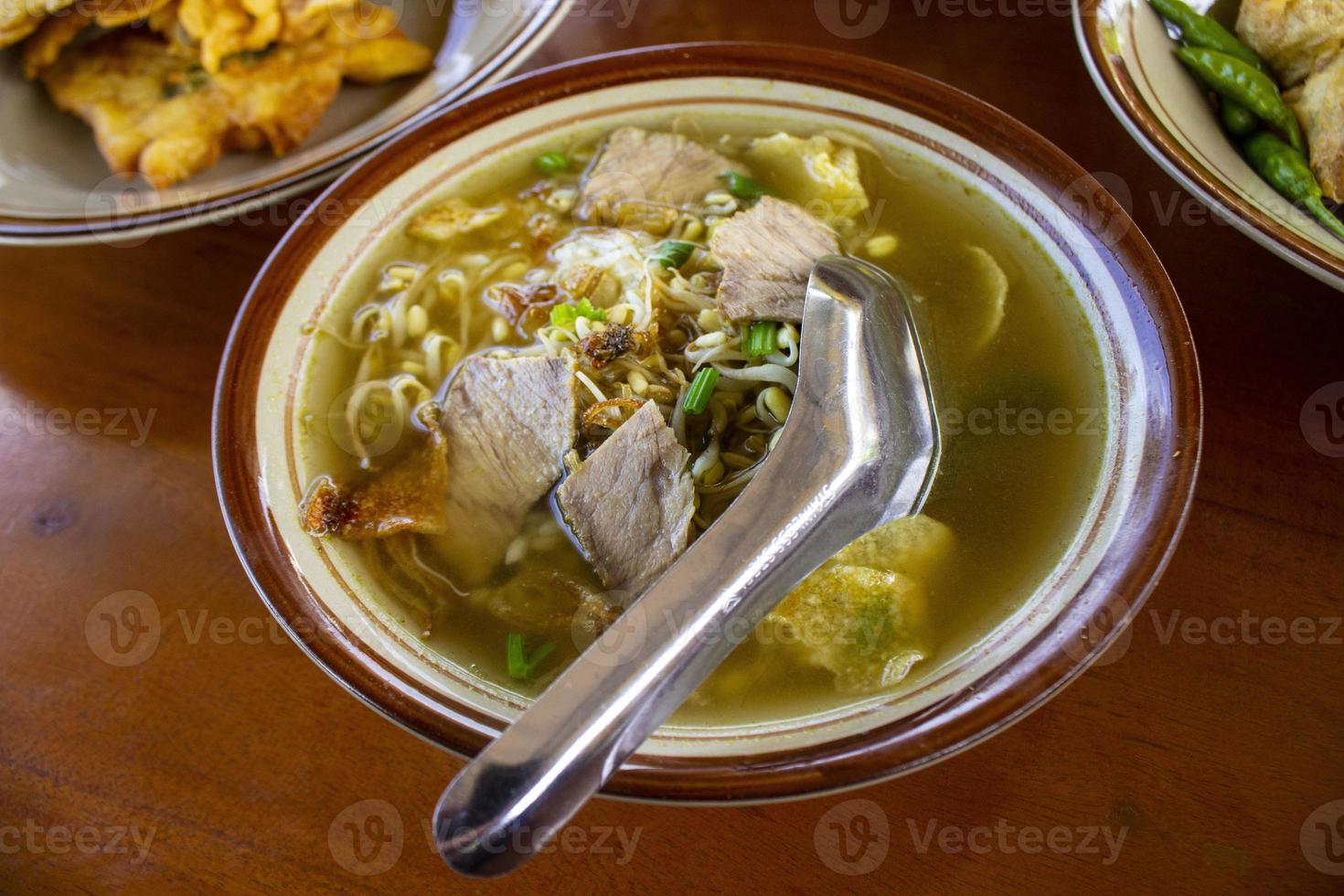 soto sapi. boeuf soto de la cuisine traditionnelle indonésienne de boyolali dans un bol blanc et fond de table en bois noir photo