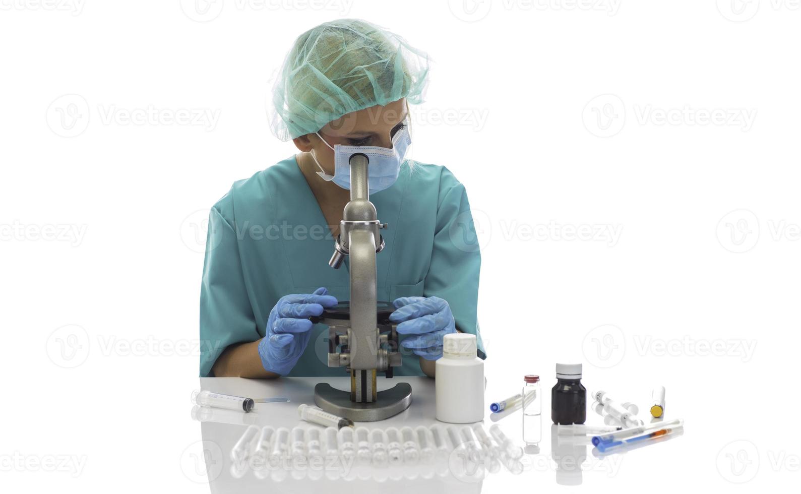 scientifique en gants médicaux bleus et uniforme d'apprentissage des échantillons de covid-19 avec microscope en laboratoire. photo