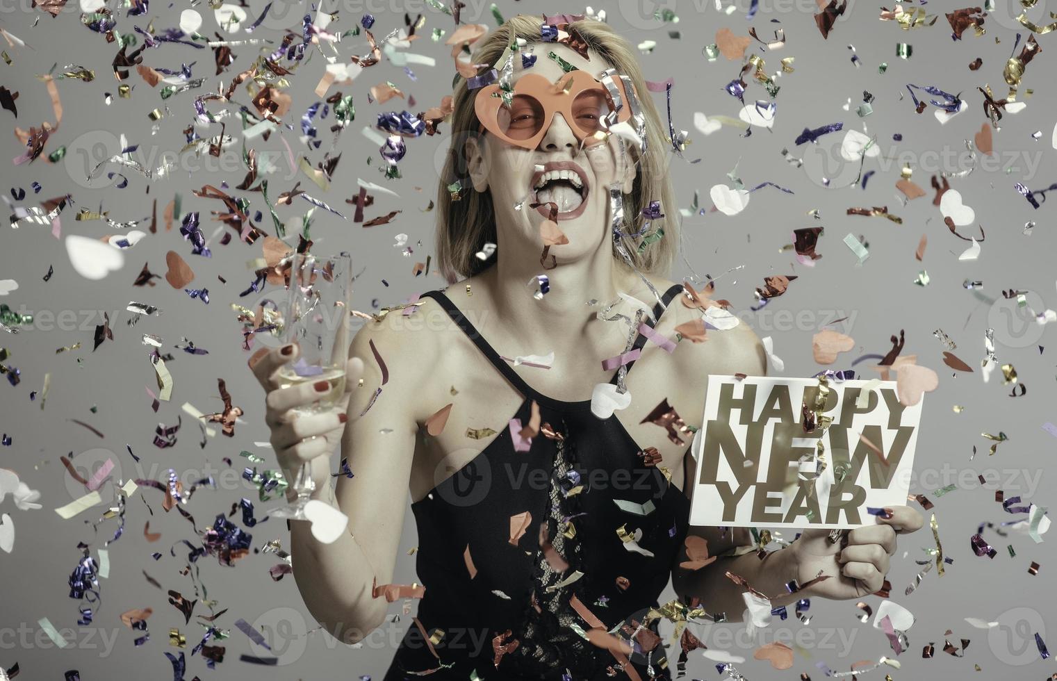 jolies femmes blondes célébrant le nouvel an tenant une pancarte bonne année. isolée photo