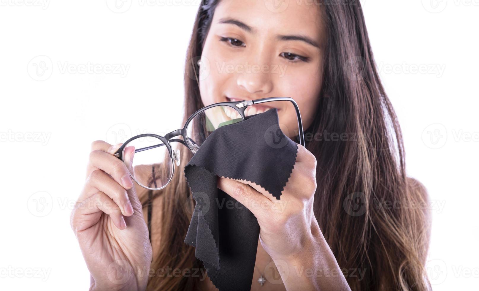 portrait d'une belle femme asiatique nettoyant ses lunettes isolées sur blanc photo