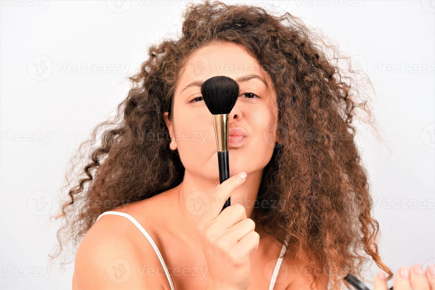 belle jeune femme souriante se maquiller avec un pinceau. isolée photo