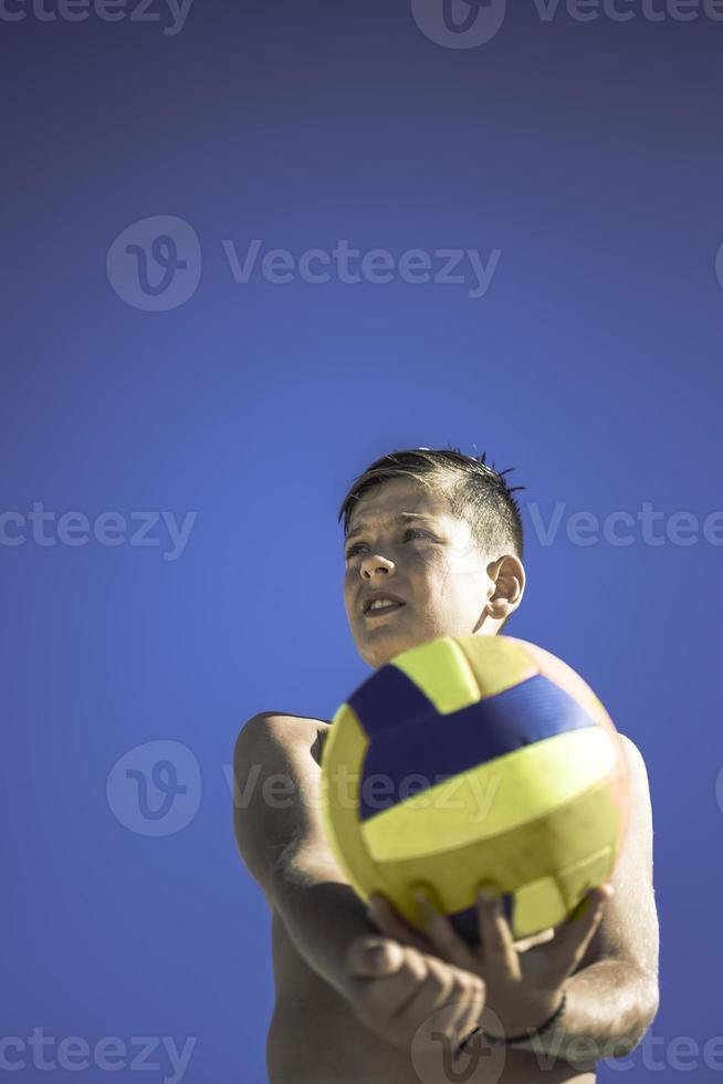 un enfant joue au volley-ball par une belle journée d'été photo