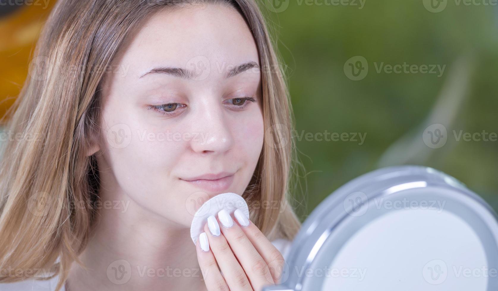 belle jeune femme nettoie son visage avec des lingettes humides. isolée photo