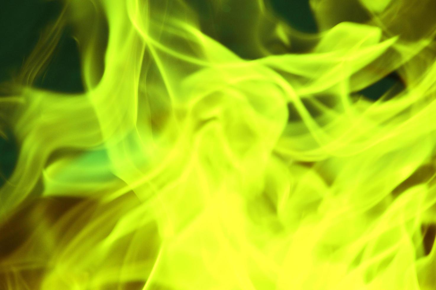 éblouissement vert et jaune vif, flammes, fumée colorée sur fond sombre. fond abstrait. photo