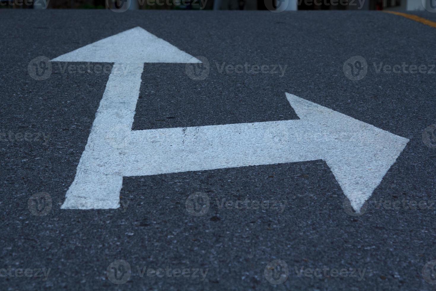 le panneau de signalisation flèche blanche sur l'asphalte noir sur la route est un symbole simple et le virage blanc est un symbole utilisé partout dans le monde. photo