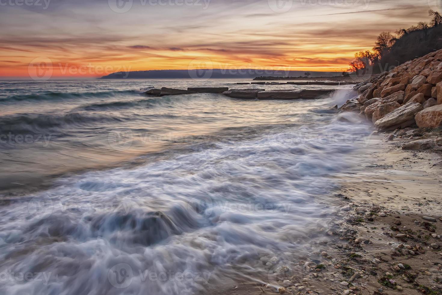 coucher de soleil sur la mer. plage de la mer de beauté avec de l'eau de flou de mouvement et des vagues qui s'écoulent. photo