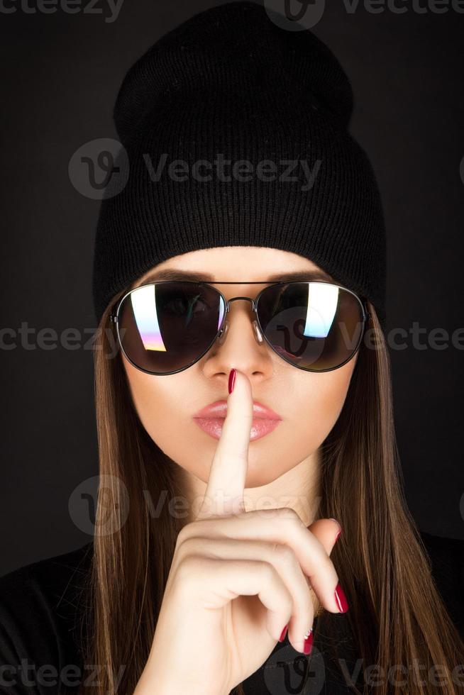 jolie jeune femme avec une peau saine dans des lunettes de soleil sur fond noir photo