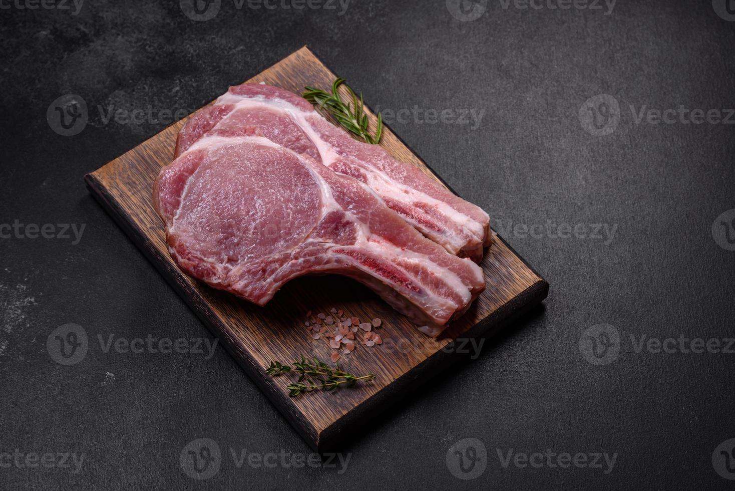 viande de porc crue fraîche sur les côtes avec des épices et des herbes sur une planche à découper en bois photo