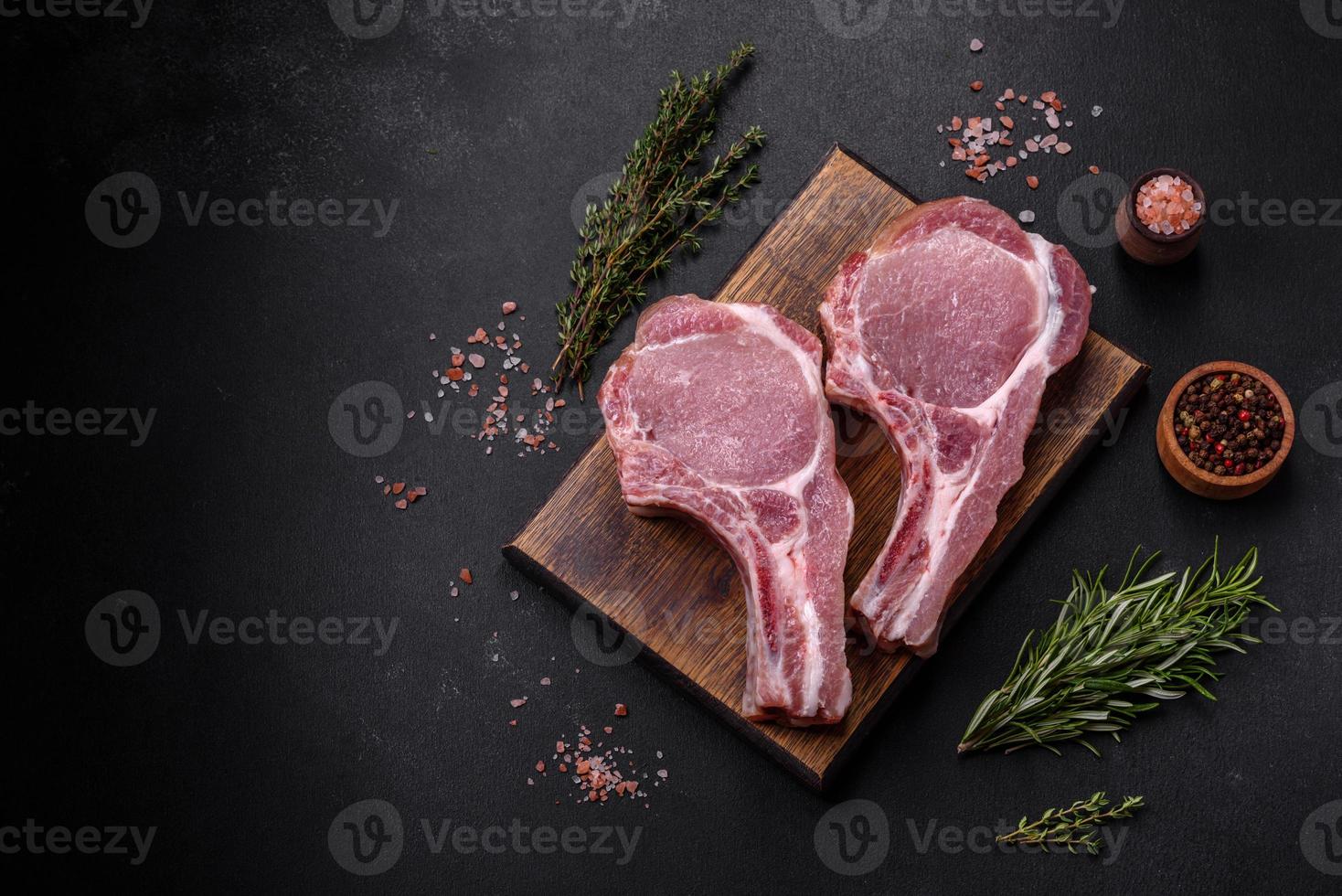 viande de porc crue fraîche sur les côtes avec des épices et des herbes sur une planche à découper en bois photo
