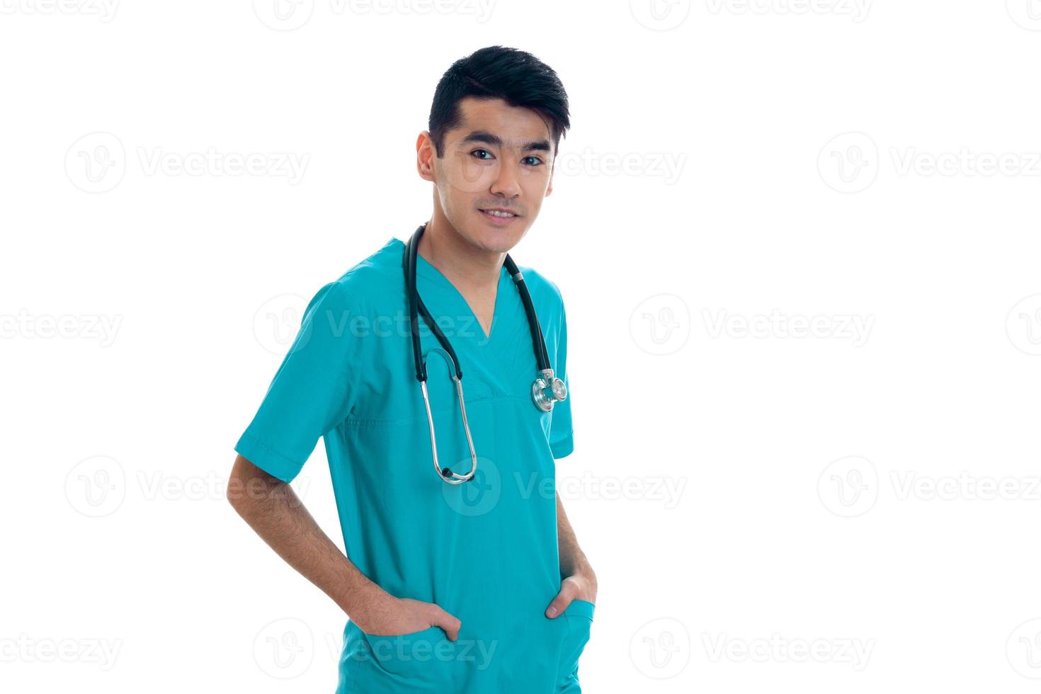 Jolie jeune homme médecin en uniforme avec stathoscope posant isolé sur fond blanc photo