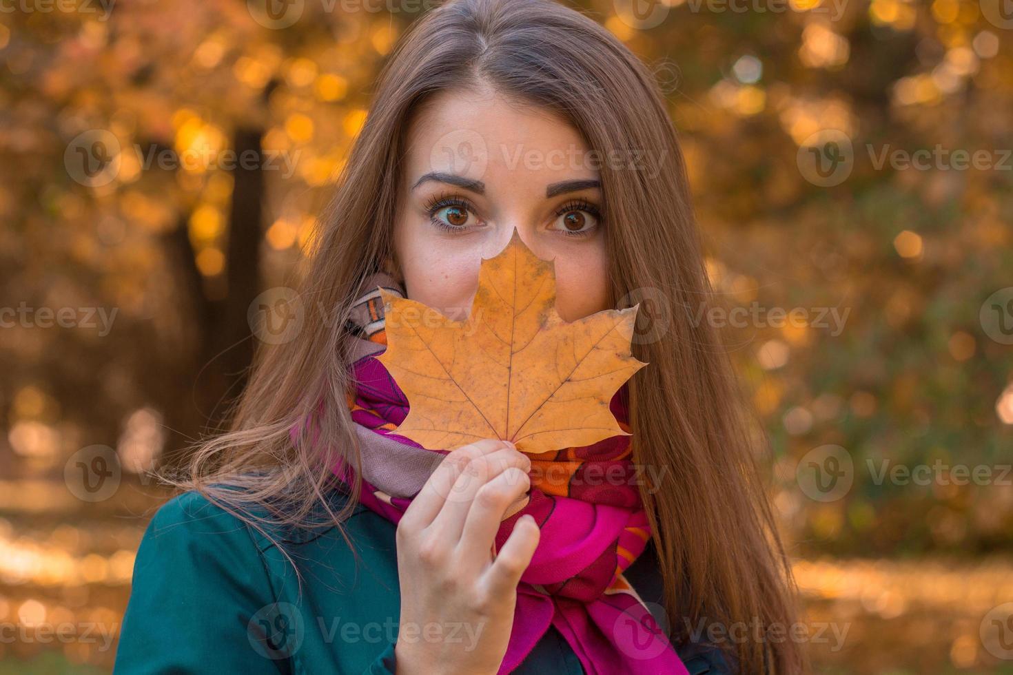 portrait d'une belle fille qui garde les feuilles sèches près de la personne dans le parc photo