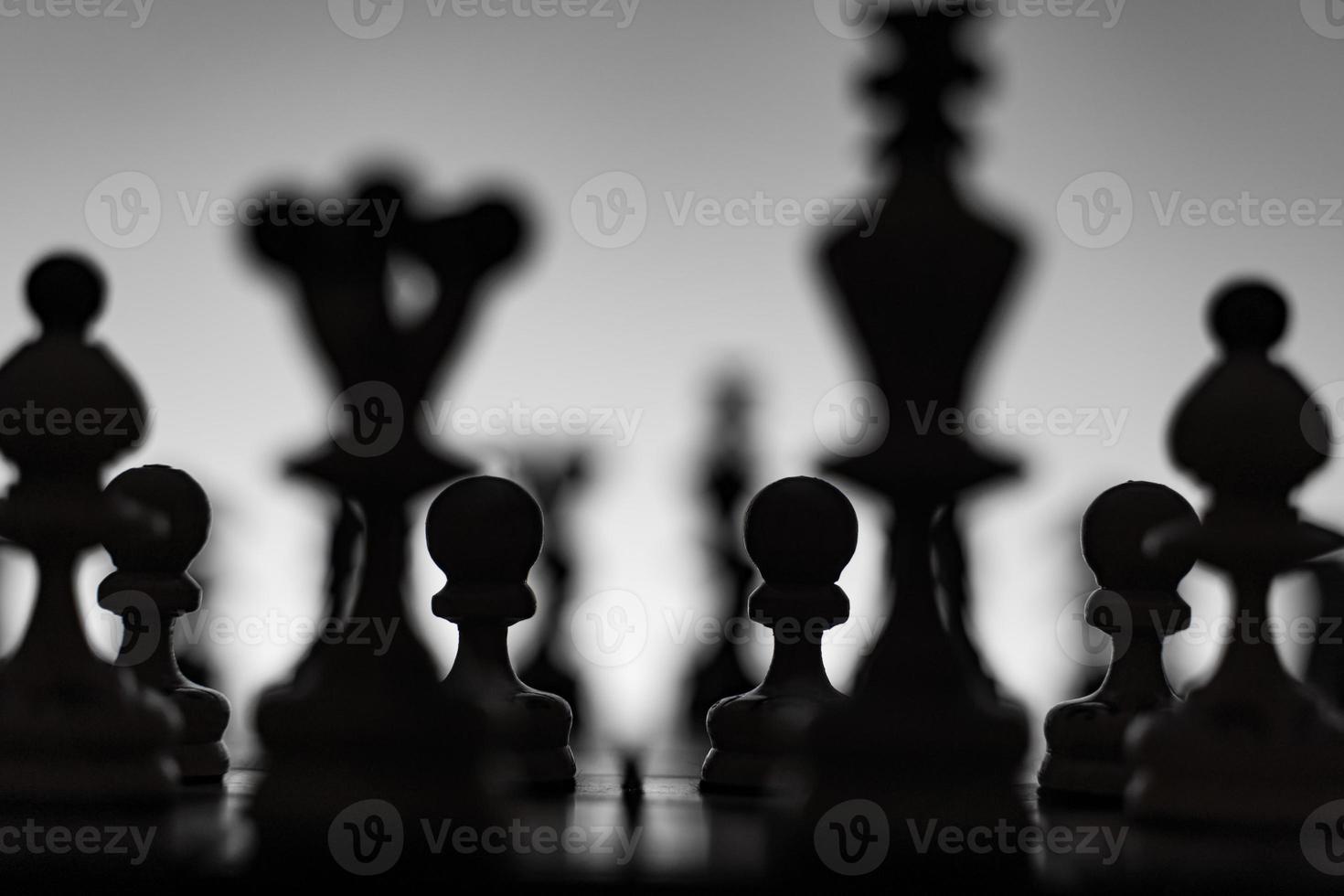 échiquier avec silhuettes de pièces d'échecs sur fond blanc. concept d'idées commerciales, de concurrence et d'idées stratégiques. photo d'art classique en noir et blanc. tous les chiffres sont prêts pour la bataille, avant l'ouverture