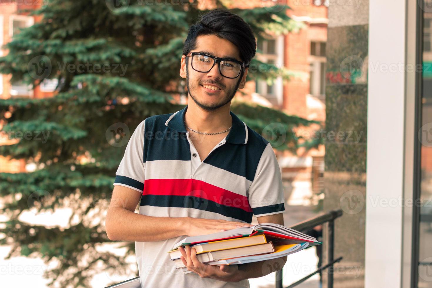 un gars souriant à lunettes regarde la caméra et garde les livres photo