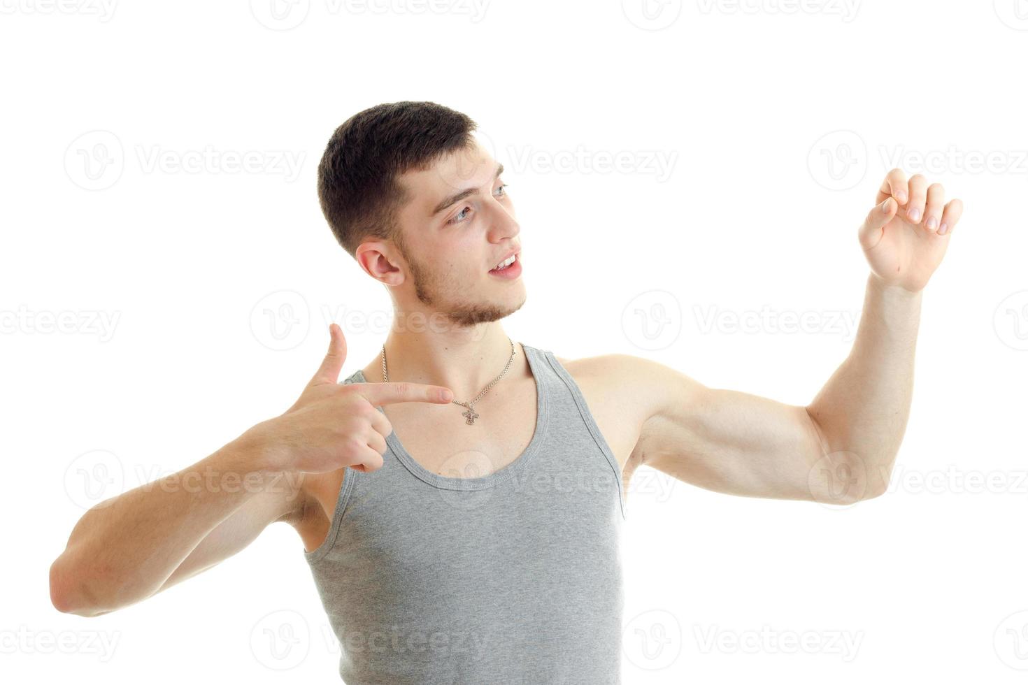 beau jeune homme dans le t-shirt regarde ailleurs et montre des gestes de mains photo