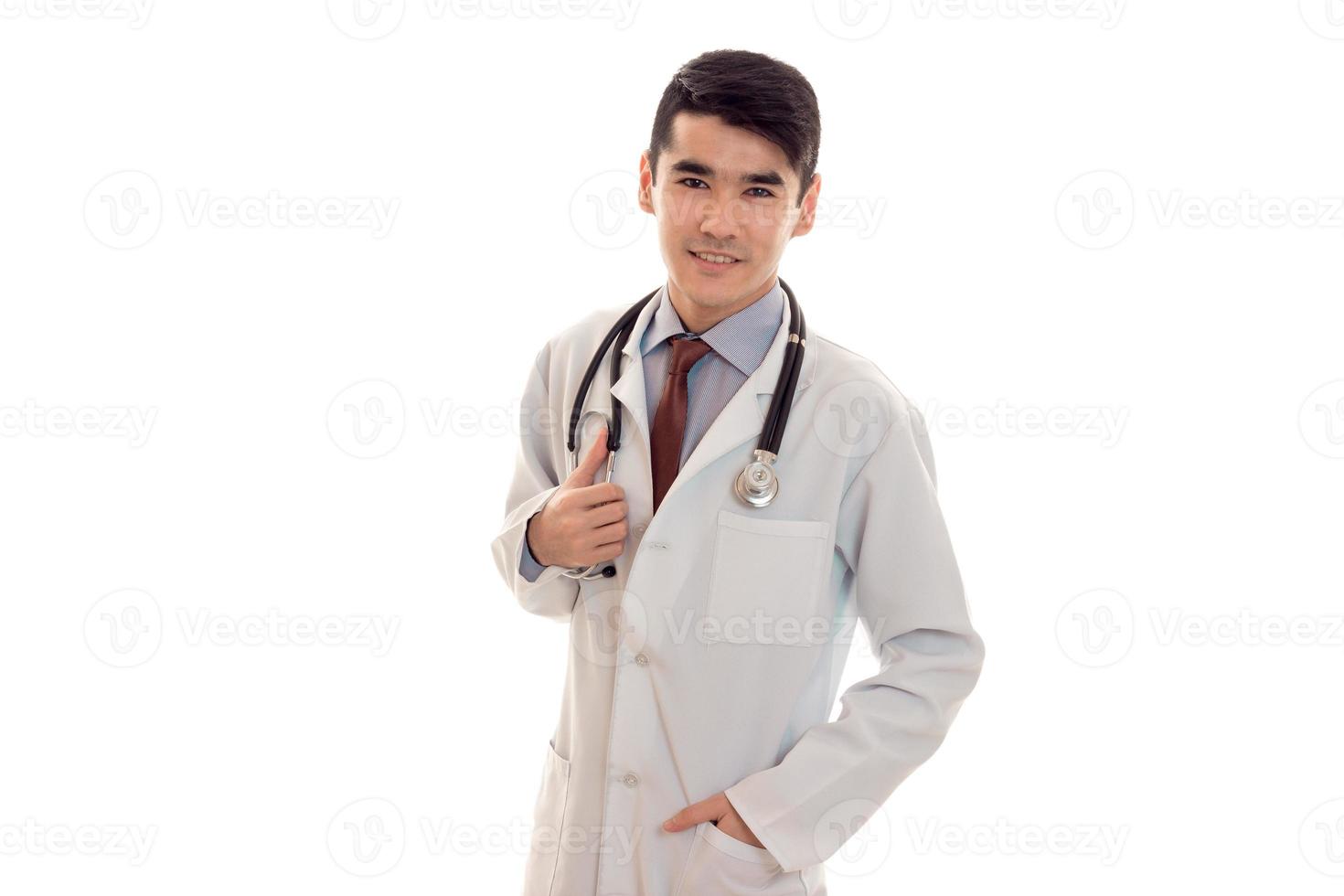 beau jeune homme médecin en uniforme avec stathoscope regardant la caméra et souriant isolé sur fond blanc photo