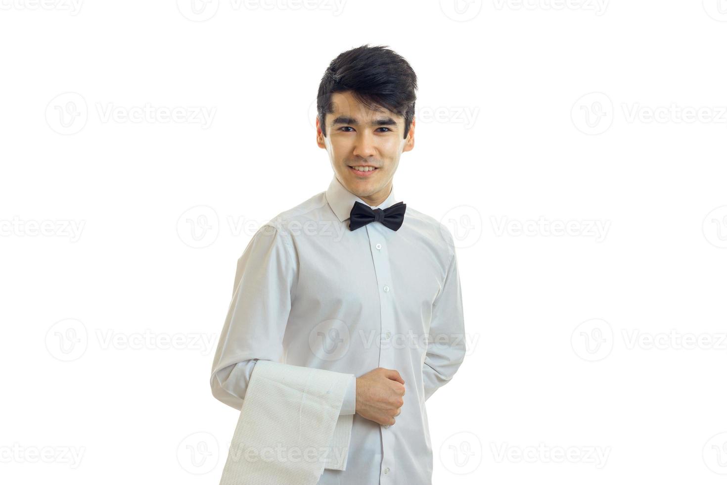 le jeune serveur tient une serviette à la main sourit et regarde dans un appareil photo