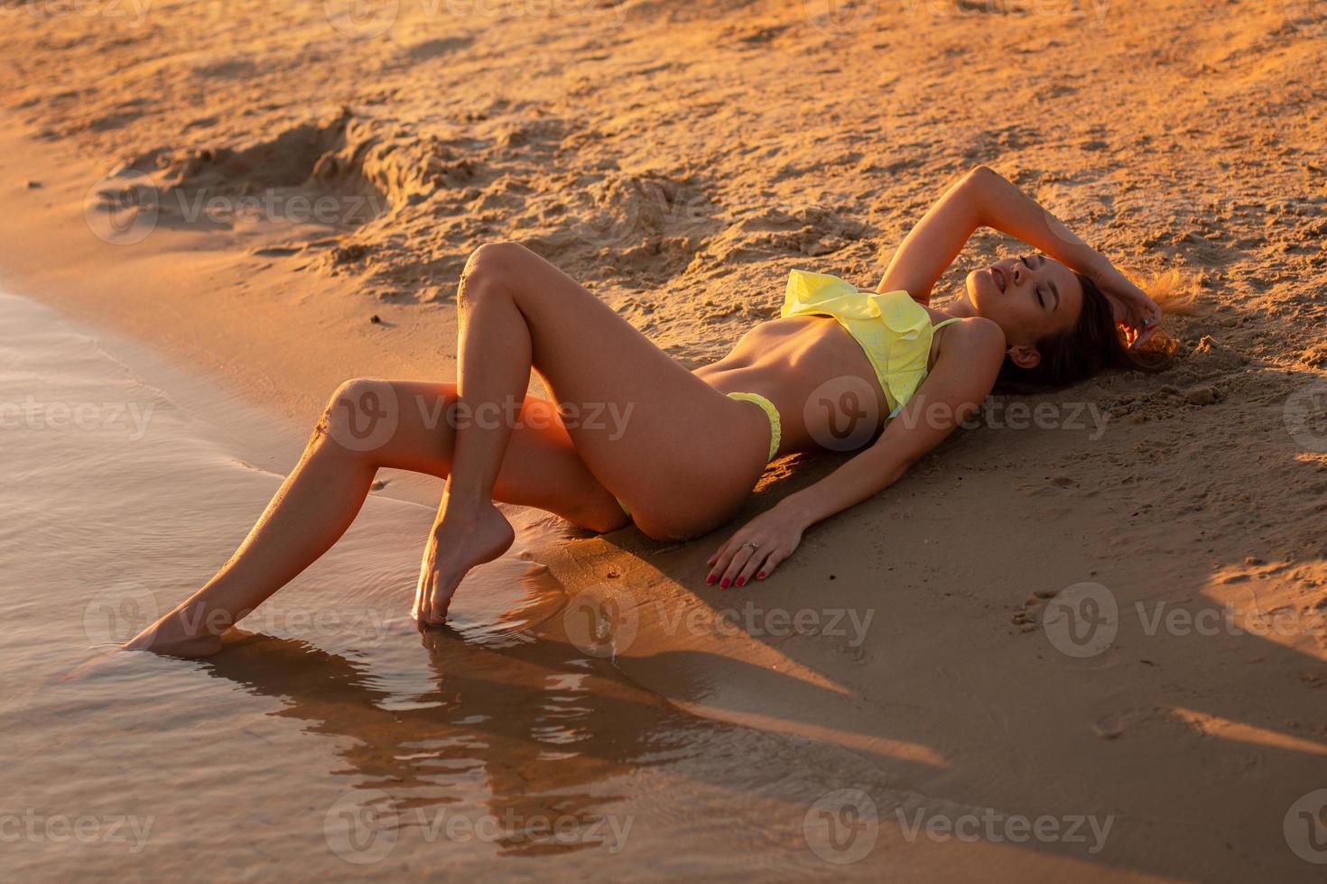 jeune fille sexy au coucher du soleil à la plage photo