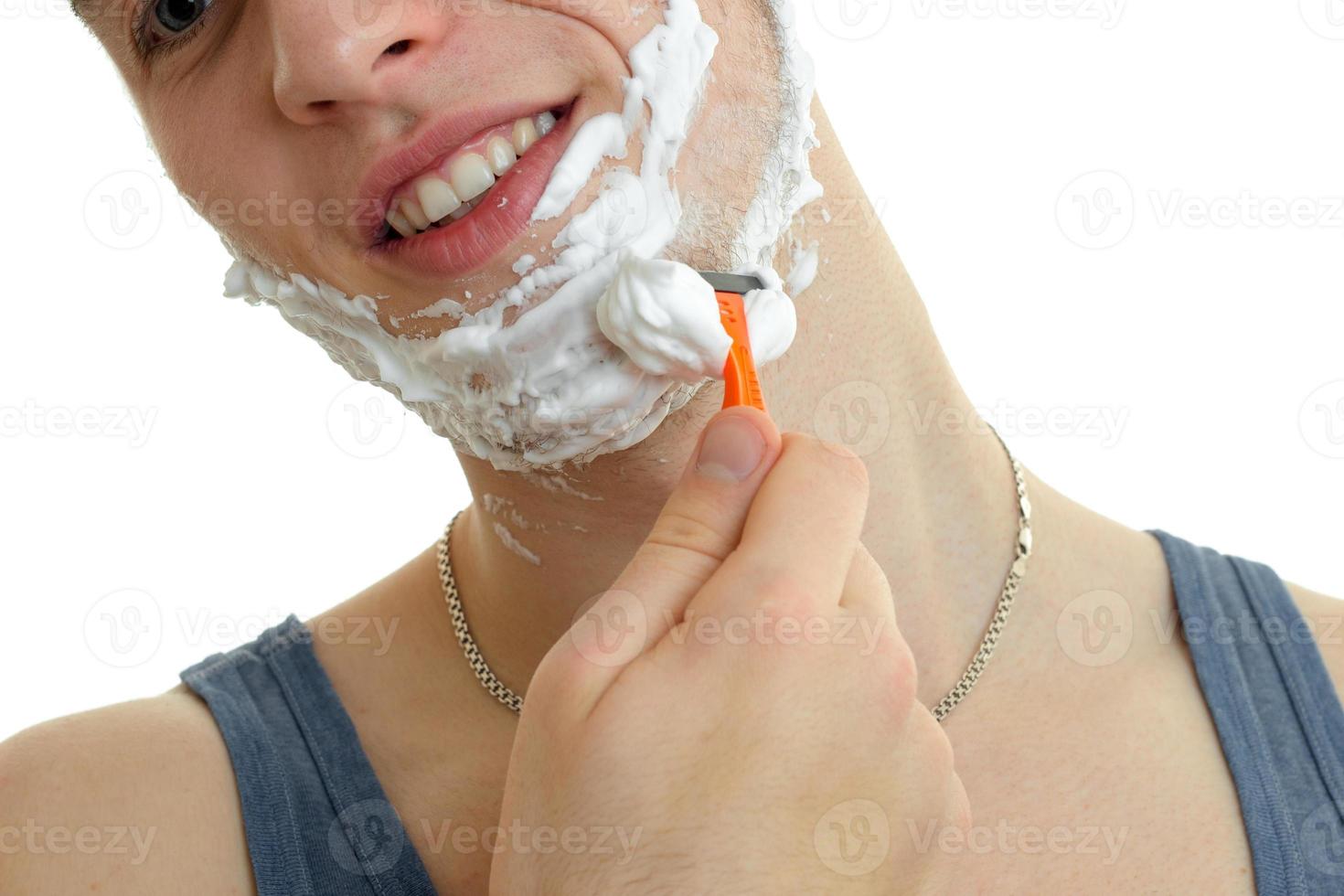 portrait d'un beau mec joyeux qui sourit et se rase la machine à barbe photo