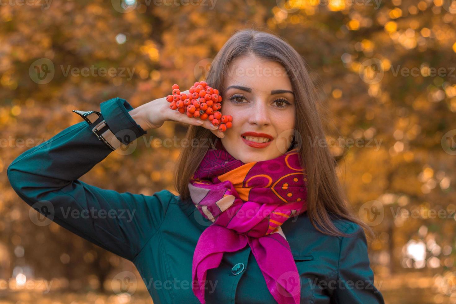 belle jeune fille dans un foulard rose et un bras de levage tient un brin de rowan en gros plan photo