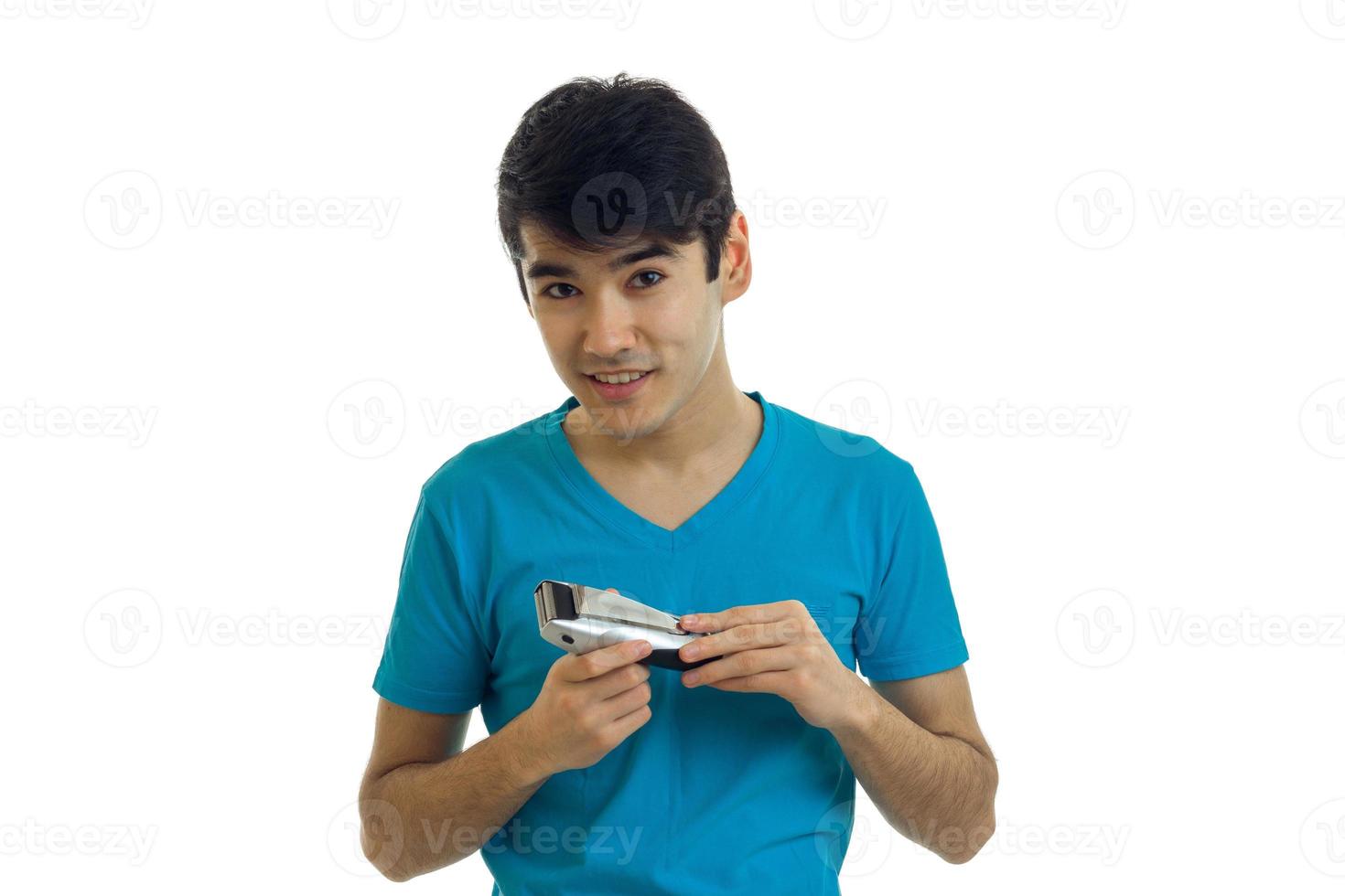 beau jeune homme aux cheveux noirs sourit et tient une tondeuse pour se raser en gros plan photo