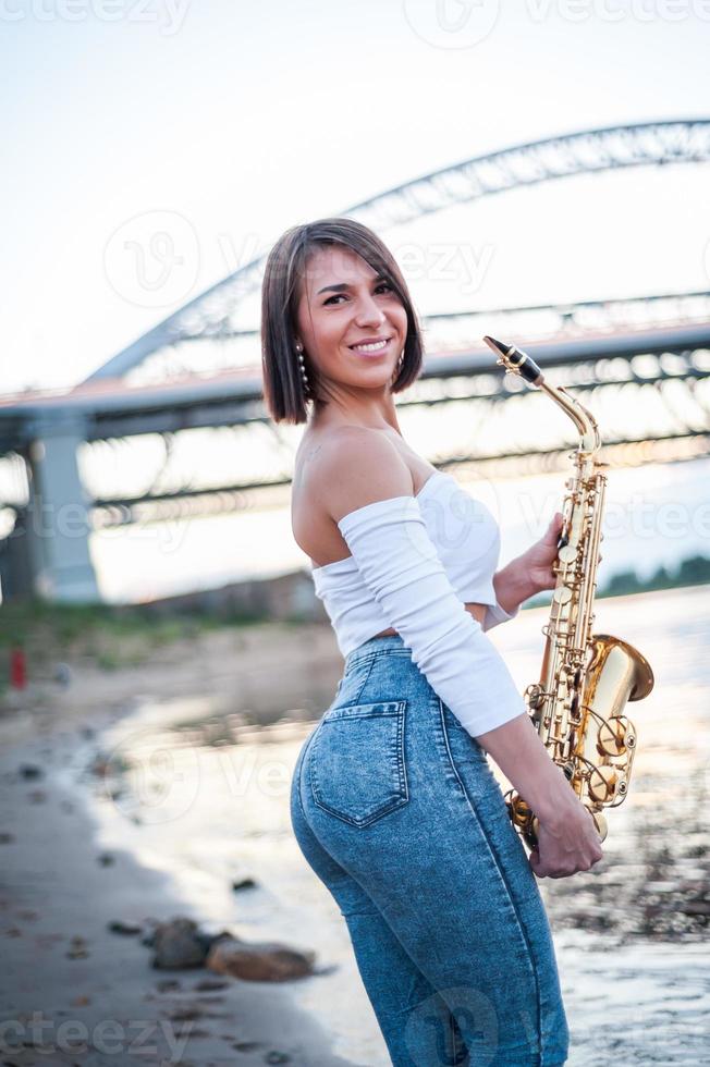 femme jouant du saxophone au coucher du soleil. photo