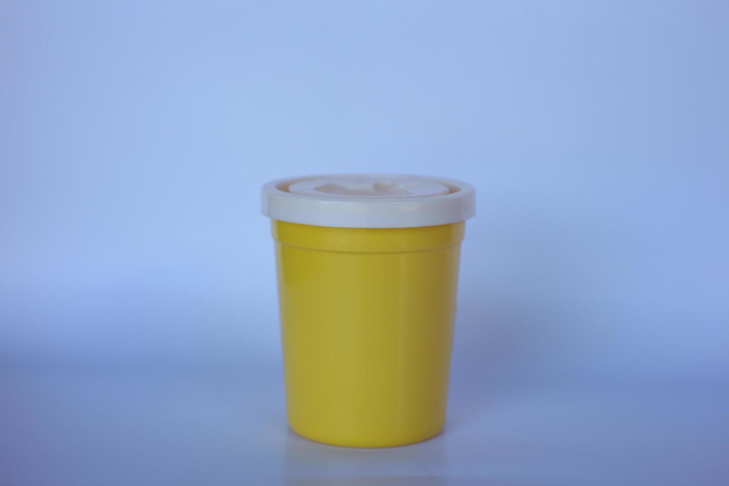 petite bouteille jaune sur un fond blanc uni. photo