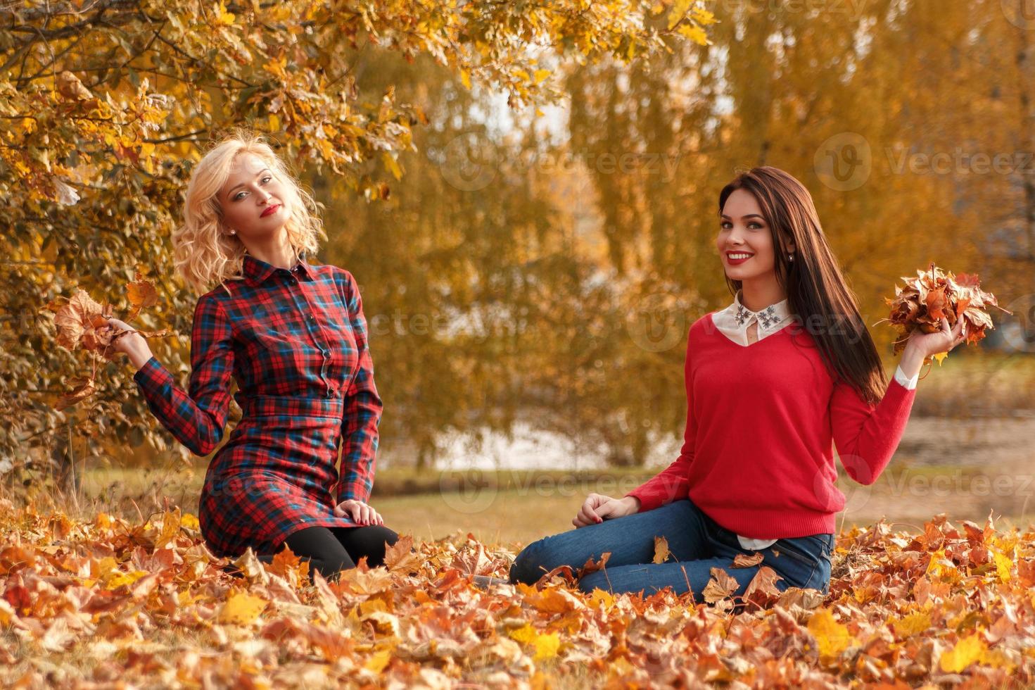 deux belles filles amies s'amusant dans le parc d'automne photo