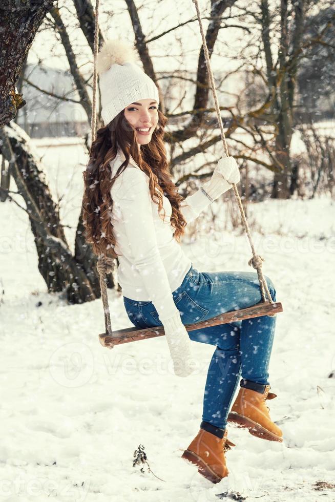 Happy girl on rope swing au jour d'hiver ensoleillé photo