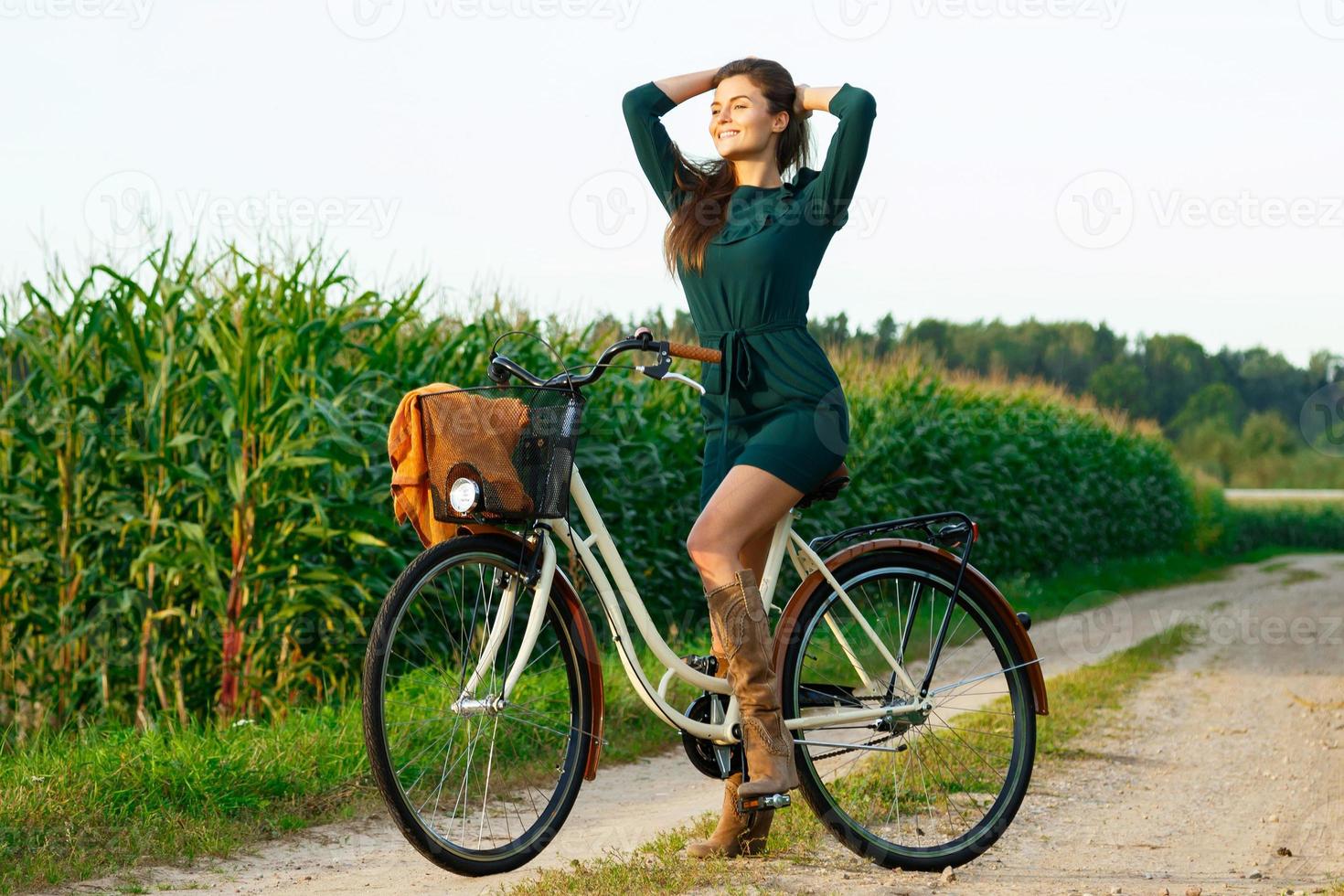 femme fait du vélo sur la route de campagne dans le champ de maïs photo