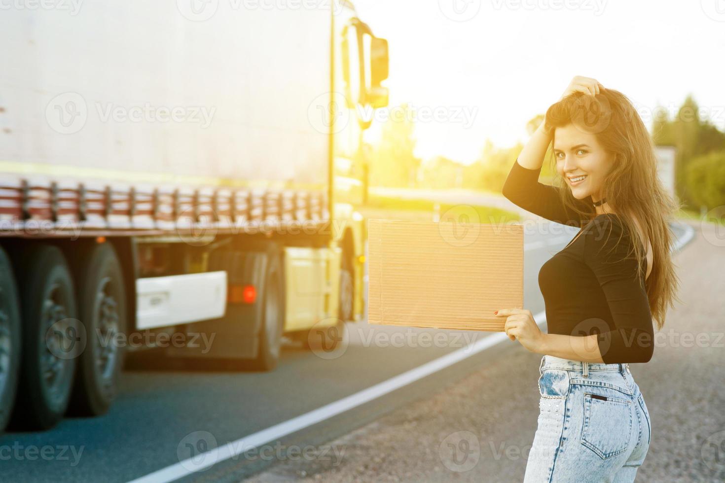 auto-stoppeur sur la route tient une pancarte en carton vierge photo