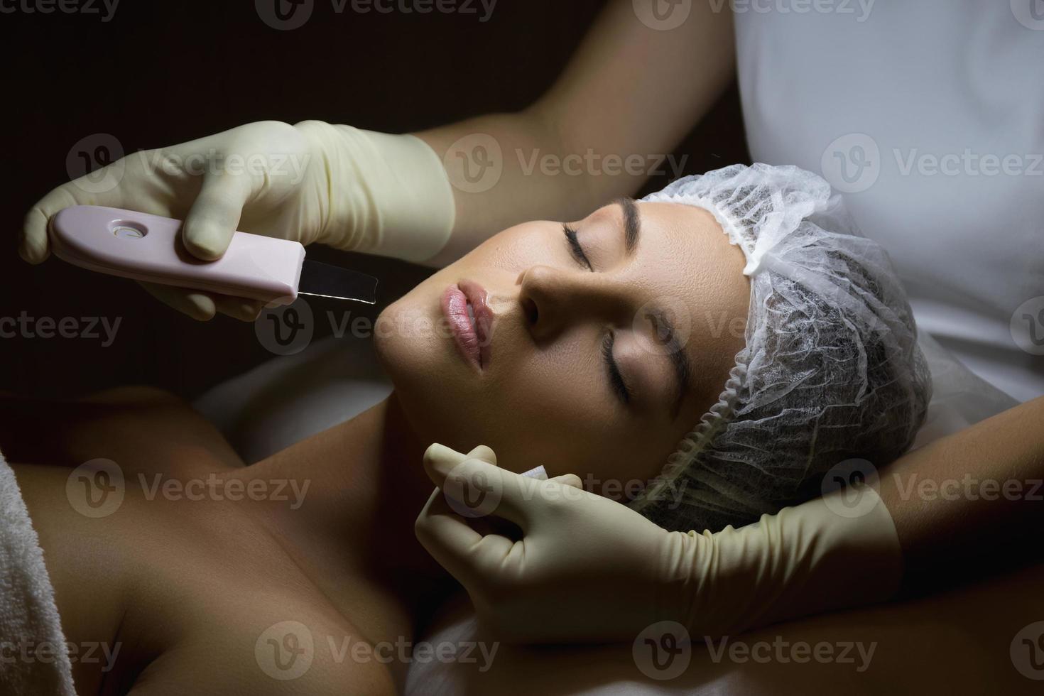 femme dans un salon de beauté professionnel pendant la procédure de nettoyage du visage par ultrasons photo