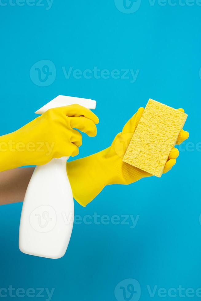 concept de nettoyant, main dans des gants en caoutchouc et tenant le flacon pulvérisateur pour pulvériser le nettoyant sur une éponge jaune photo