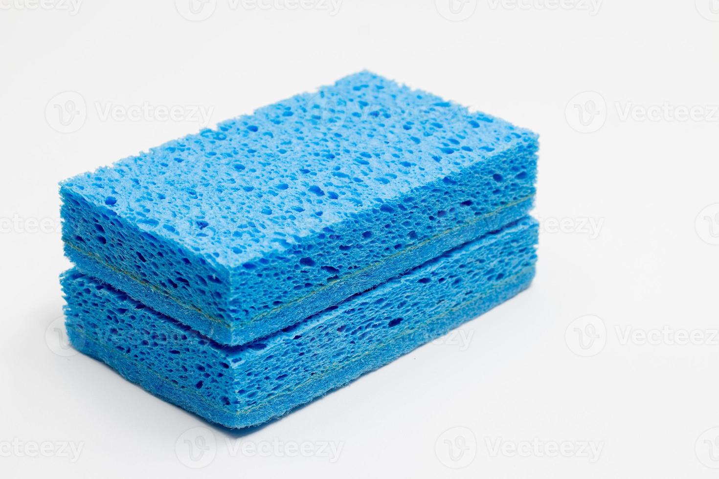 concept de nettoyage, éponge bleu clair pour le lavage de la vaisselle dans la cuisine empilée isolée sur fond blanc photo