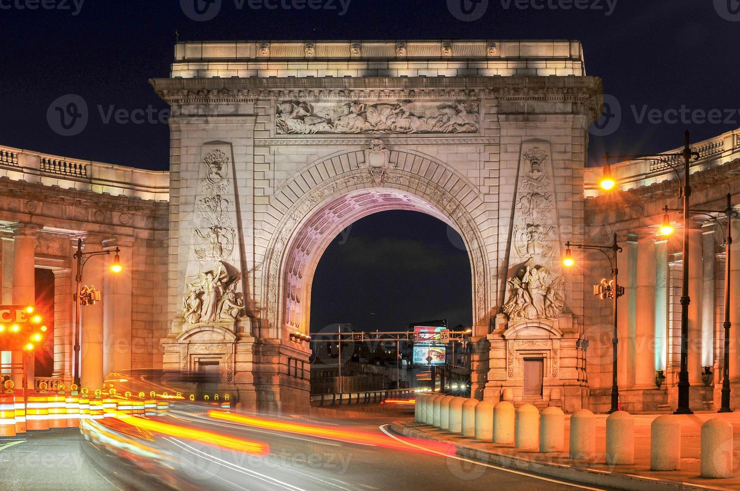 trafic circulant à travers l'arche du pont de manhattan et l'entrée de la colonnade à new york, états-unis photo