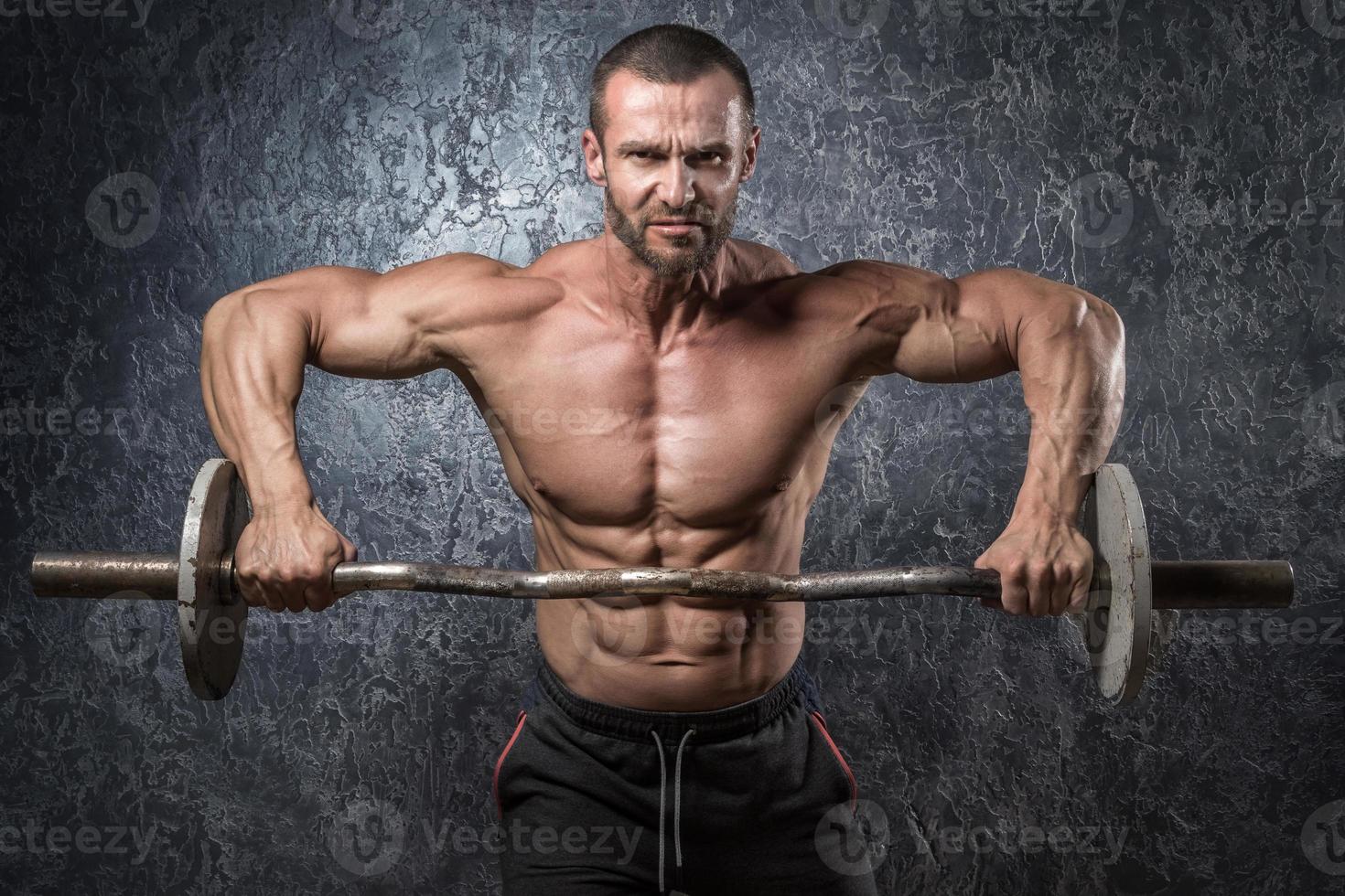 Homme bodybuilder avec barbell contre mur de béton photo