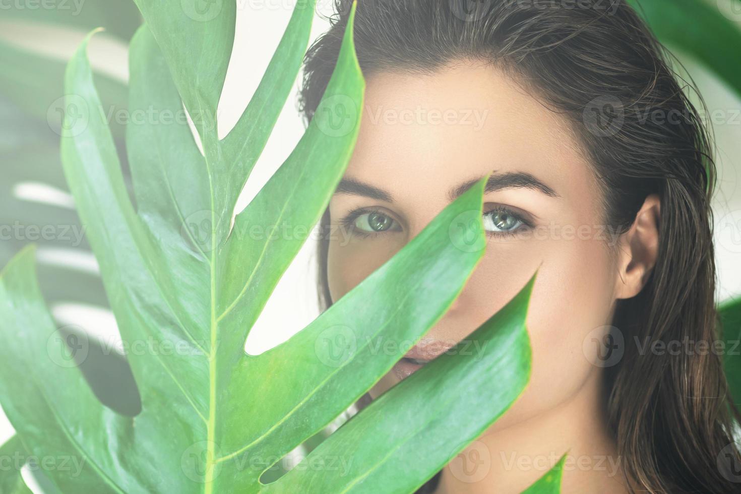 portrait de jeune et belle femme avec une peau lisse parfaite dans les feuilles tropicales. photo