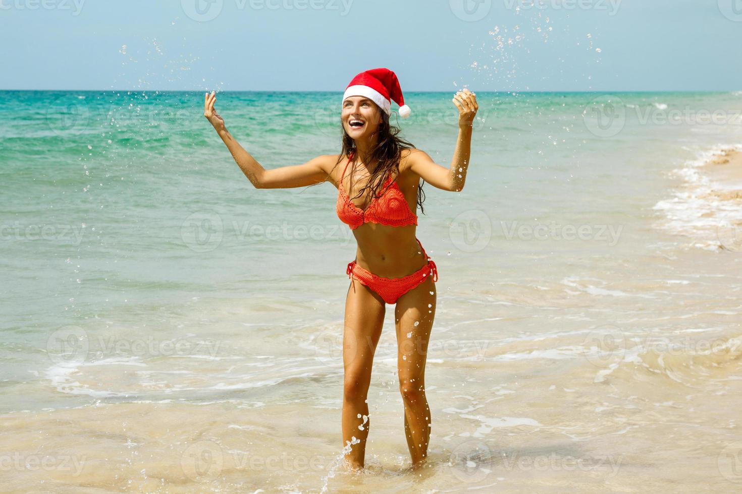 femme portant un bikini et un chapeau de noël sur la plage. vacances d'hiver dans les pays chauds. photo