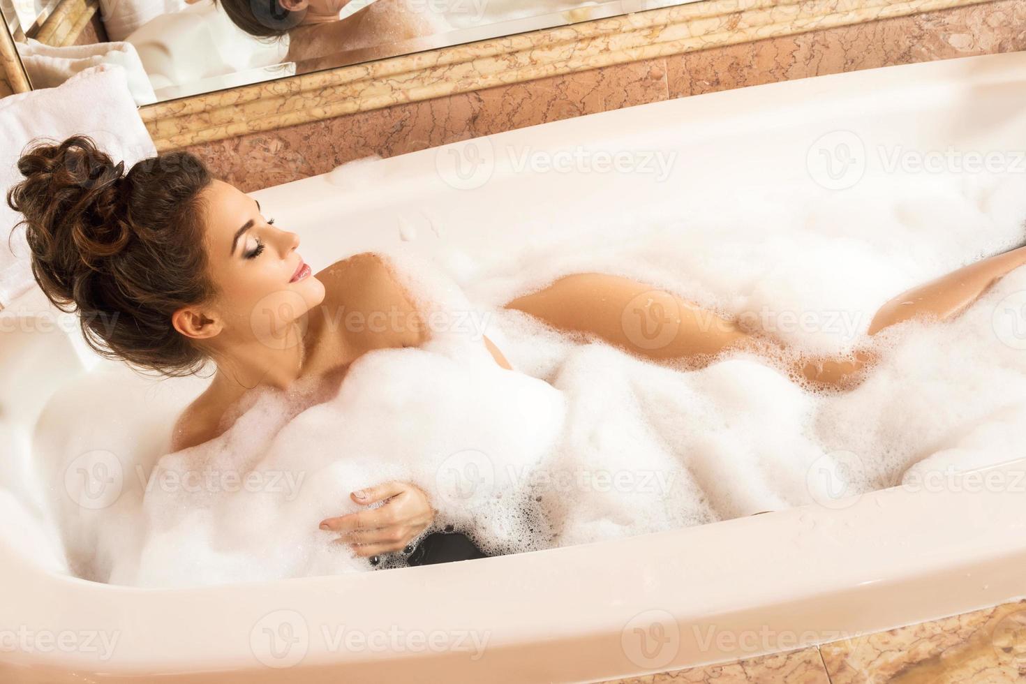 femme heureuse et belle prend un bain avec une mousse photo