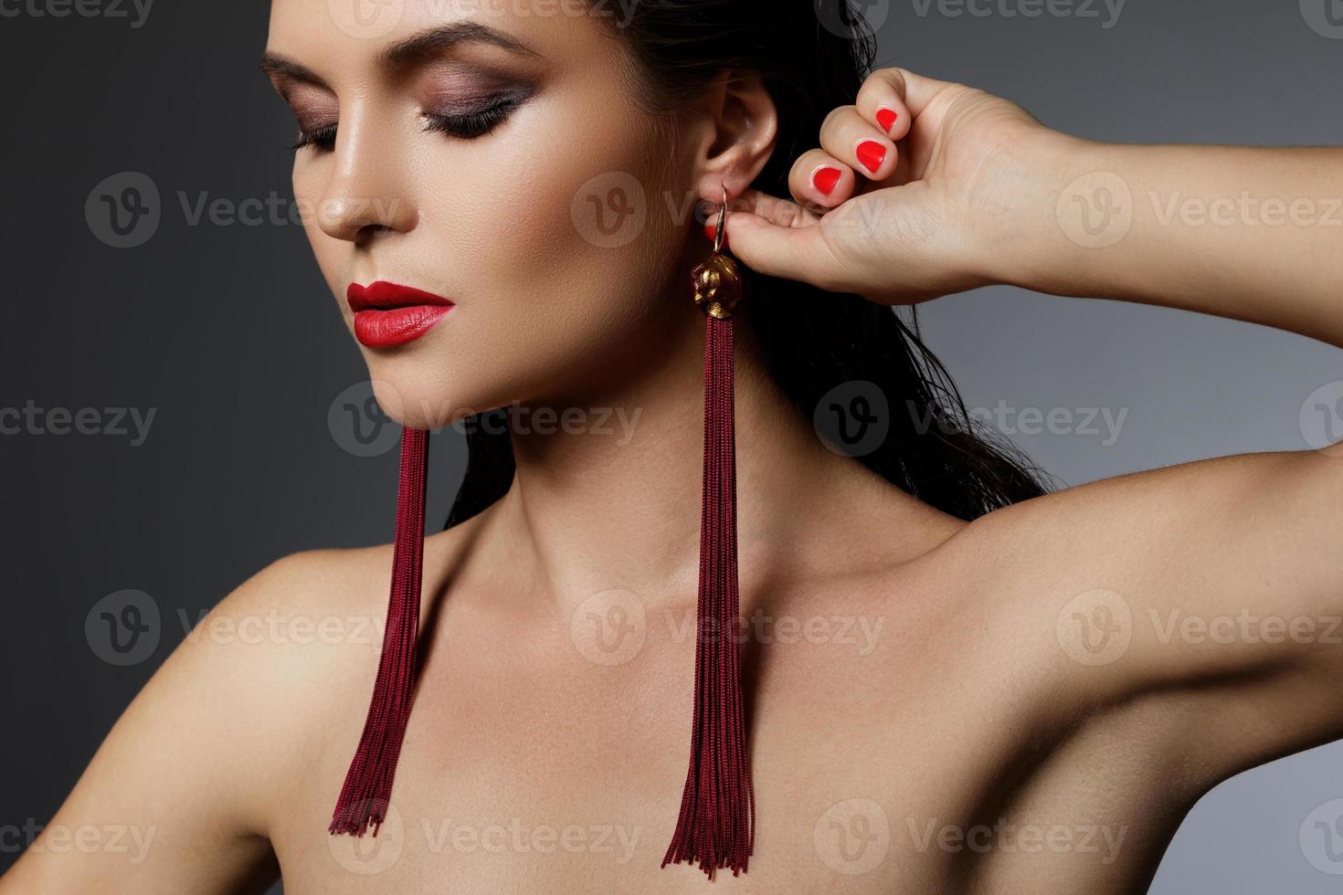 superbe femme avec un beau maquillage portant de longues boucles d'oreilles rouges photo