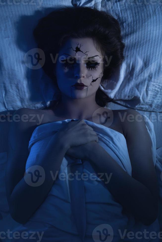 poupée parlante en porcelaine fantasmagorique tenant un couteau et allongée dans le lit photo
