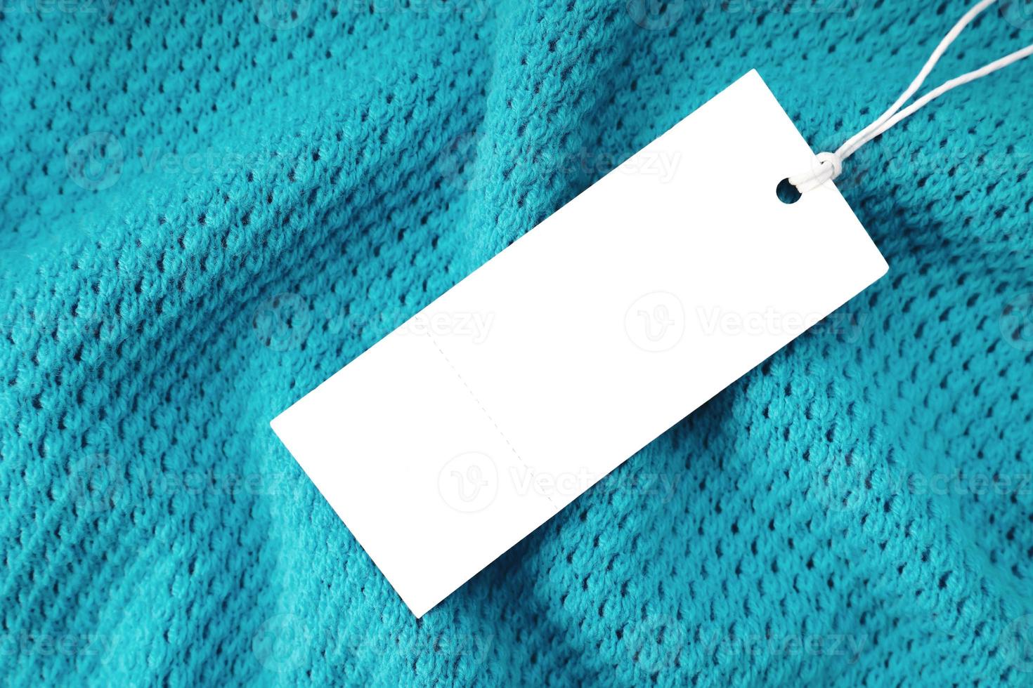 étiquette de vêtement rectangulaire blanche sur fond de tricot turquoise. shopping, vente, rabais photo