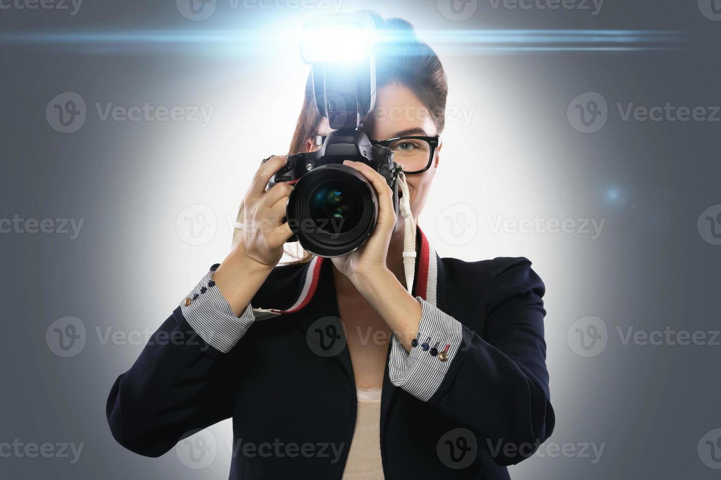 Femme photographe avec appareil photo reflex numérique à l'aide de flash