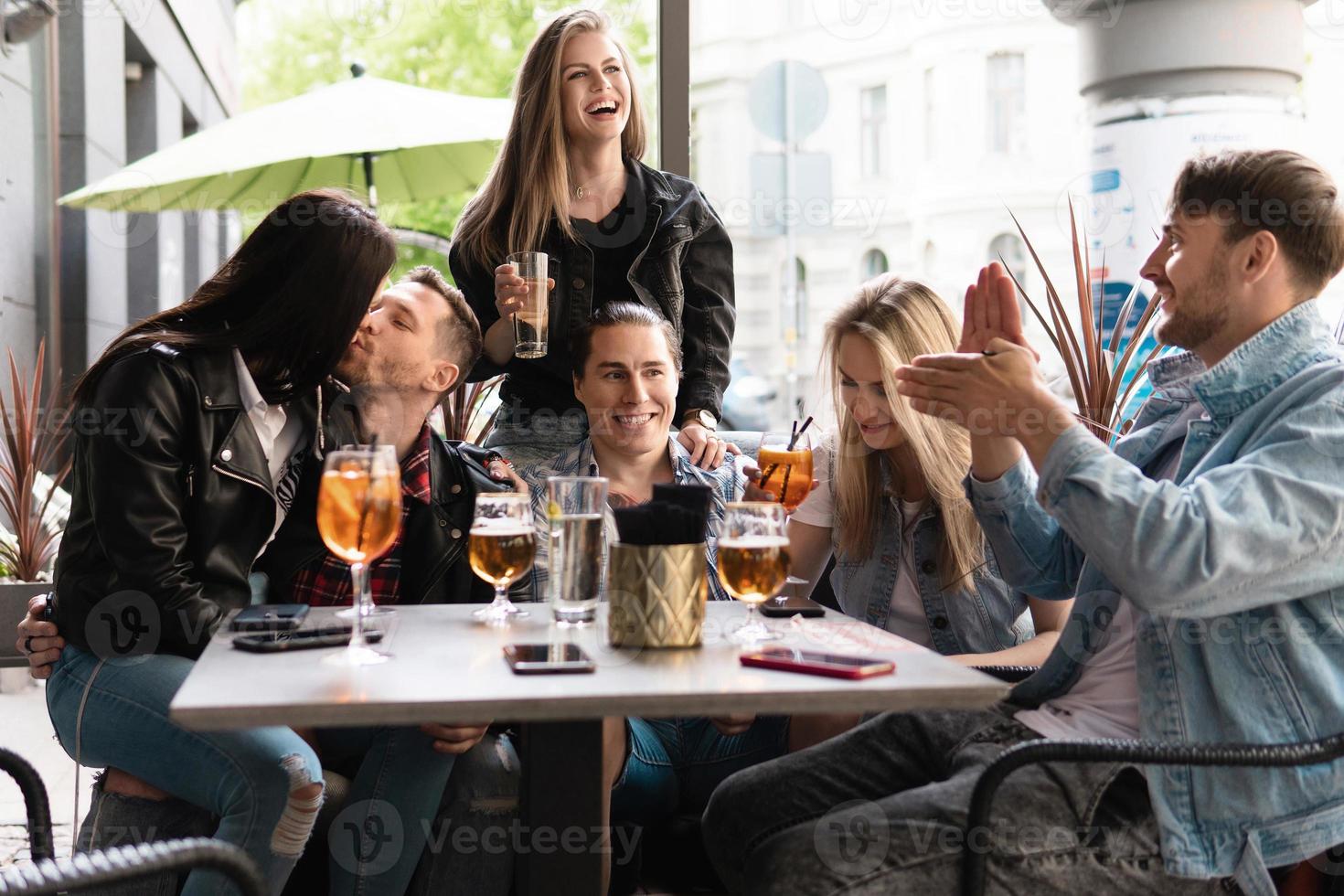 un groupe d'amis boit de la bière et des cocktails dans un bar photo