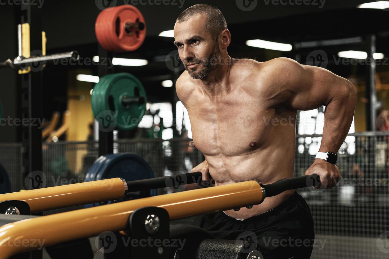 bodybuilder musclé faisant des trempettes pour les triceps et les muscles de la poitrine dans la salle de gym photo