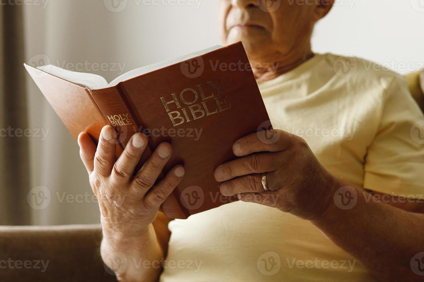 homme âgé lisant la sainte bible à la maison photo