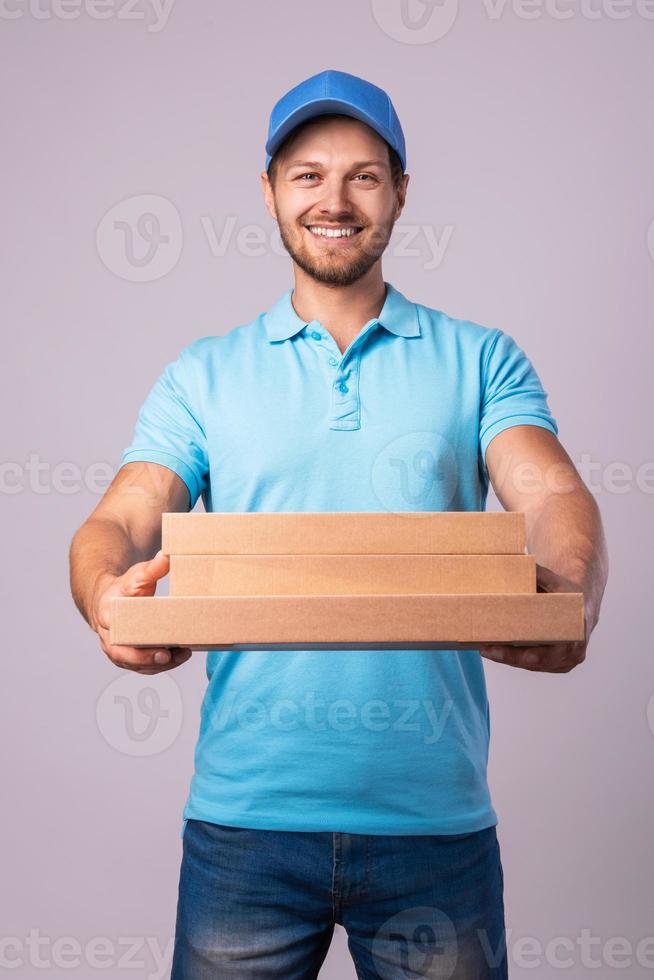 jeune livreur tient des boîtes avec une délicieuse pizza photo