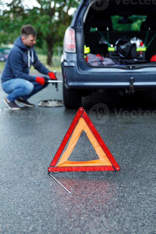 triangle d'avertissement et homme changeant de roue de voiture photo