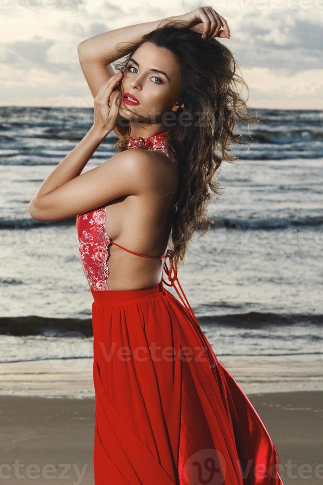 superbe femme vêtue d'une belle robe rouge sur la plage photo