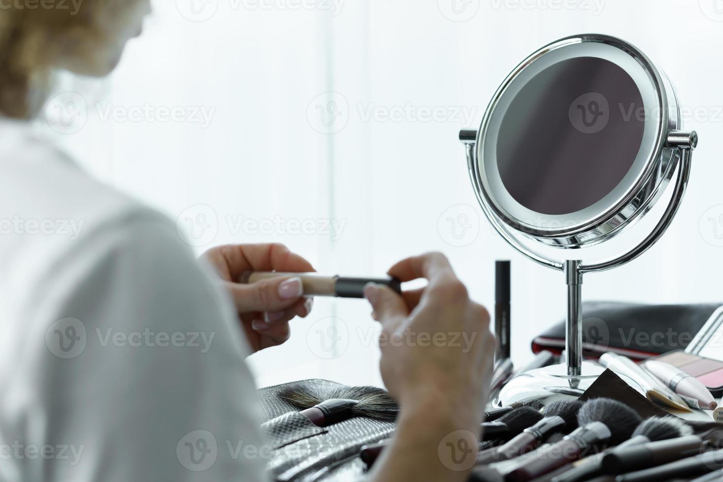 miroir rond pour le maquillage et les mains féminines avec un correcteur liquide photo