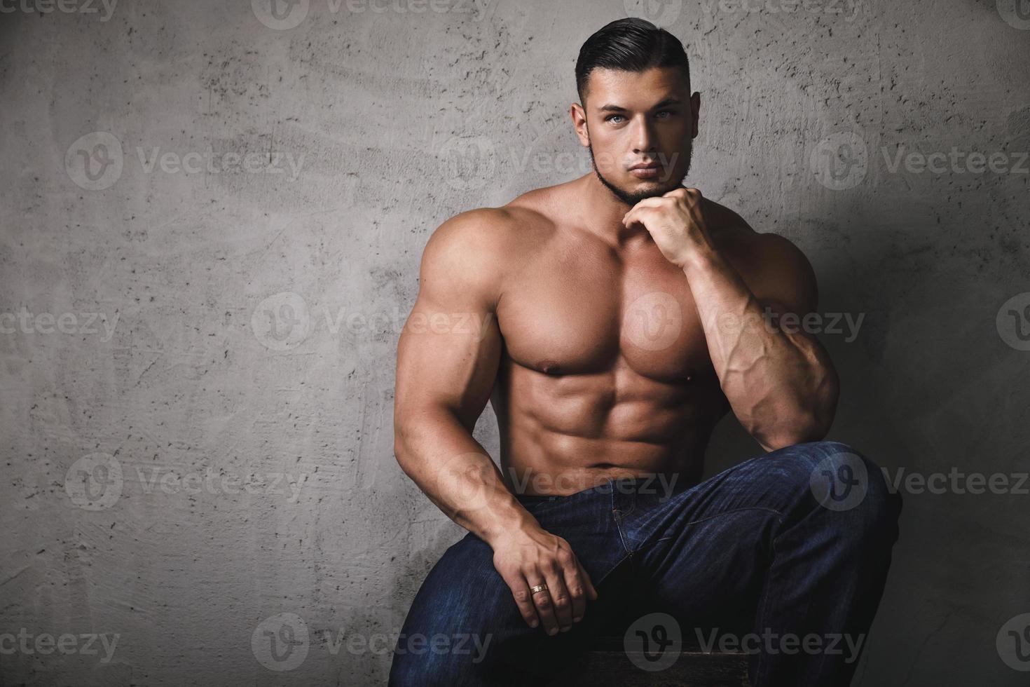 bodybuilder massif posant à côté du mur de béton photo